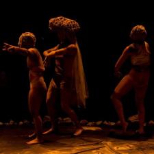 Tres personas bailando dentro de un circulo de piedras. 