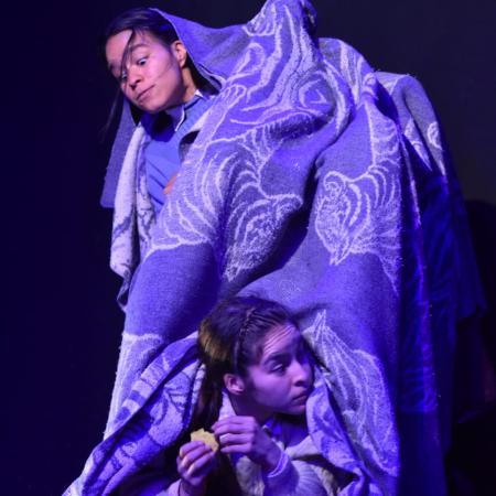 Dos mujeres bailando cubiertas con una cobija. 