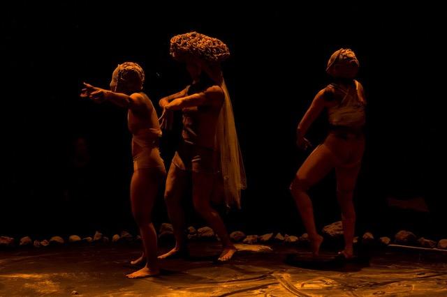 Tres personas bailando dentro de un circulo de piedras. 