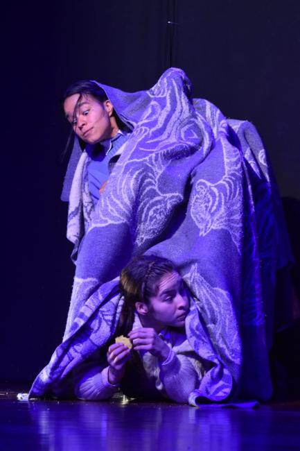 Dos mujeres bailando cubiertas con una cobija. 